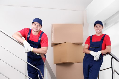 Boxes and furniture being carried down apartment stairs in West London